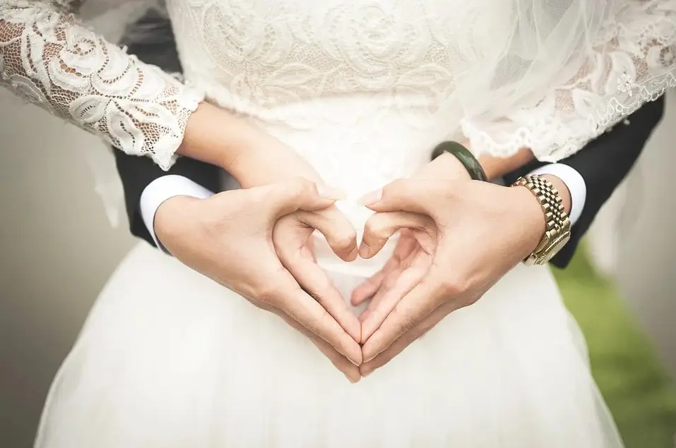 Newlywed couple’s hands forming a heart shape over the bride’s lace dress as part of their wedding raffle celebration.