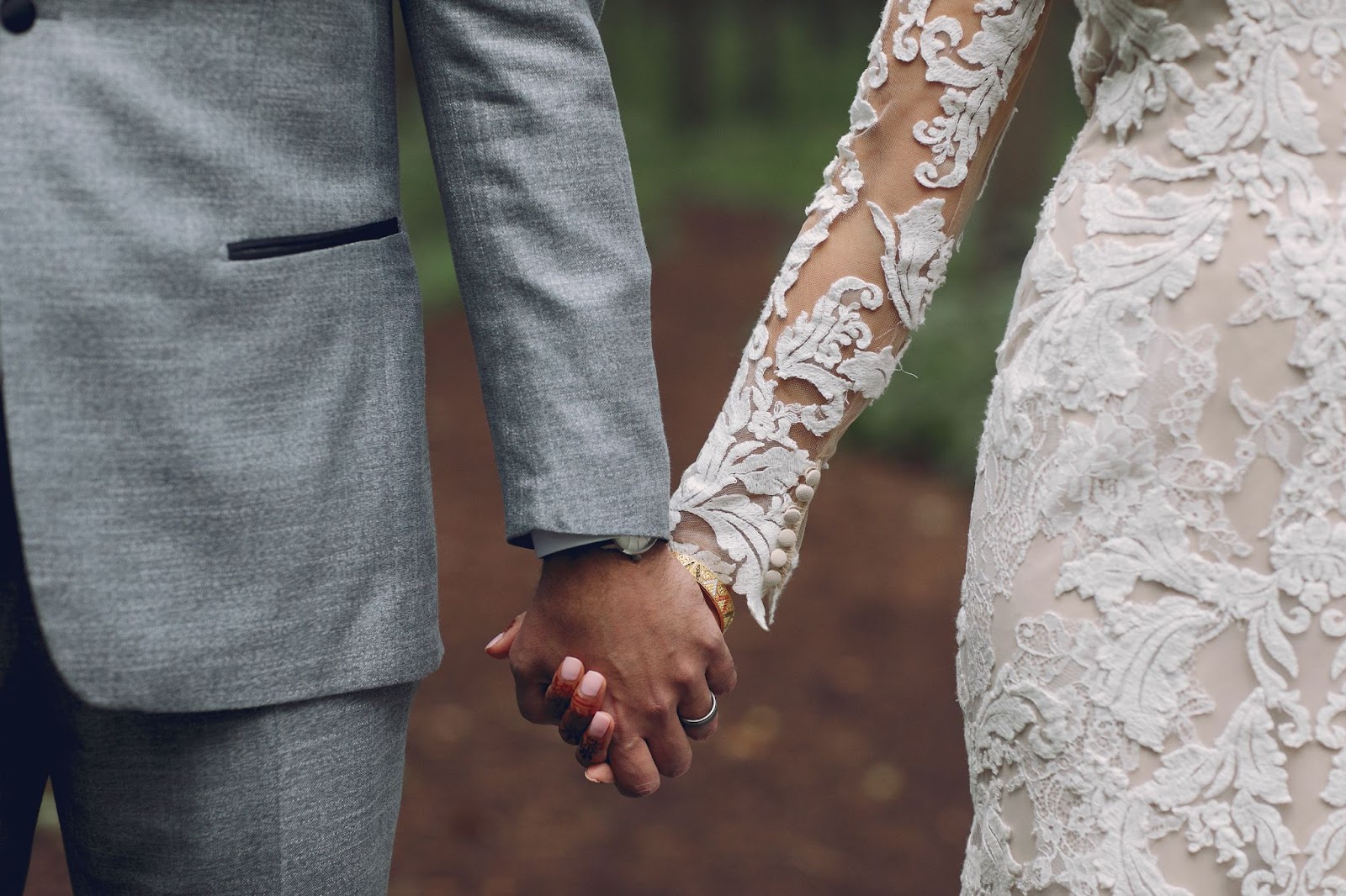 Close-up of an elegant couple holding hands in wedding attire, showing how wedding competitions help turn heartfelt commitments into affordable dream weddings.