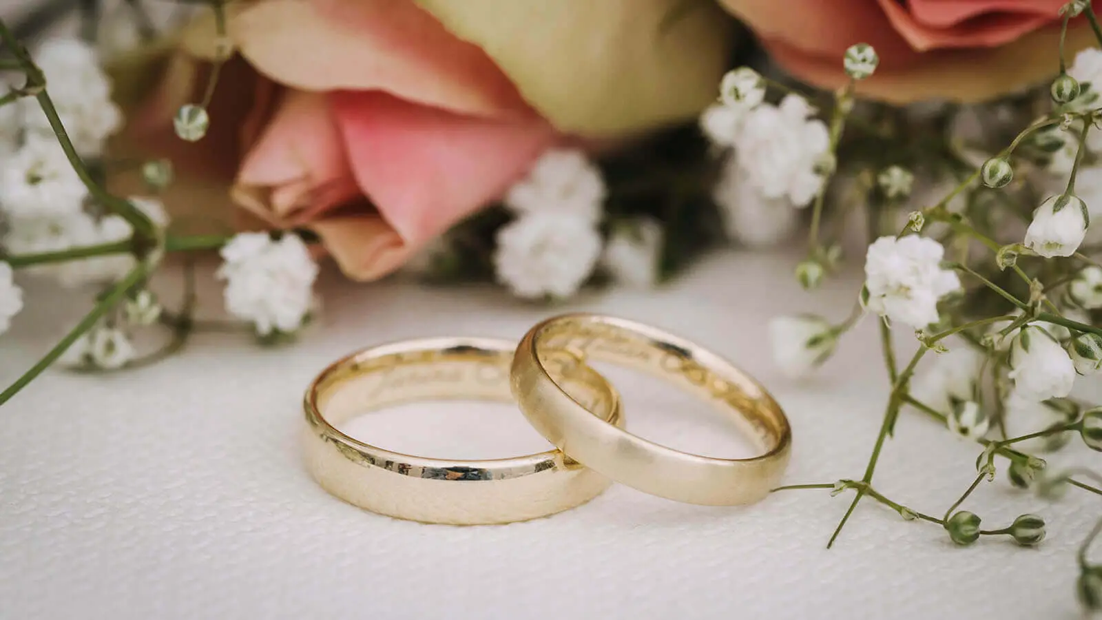 Gold wedding rings with white flowers and pink roses for wedding raffles prize display