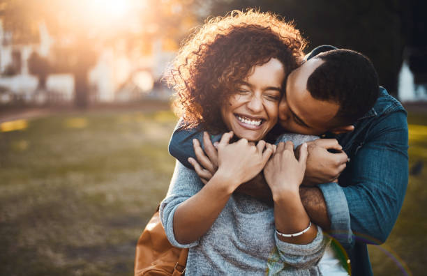 Happy couple embracing outdoors with golden sunlight while winning wedding cash prizes by sharing their authentic love story through heartfelt competition entries like A Day 2 Remember's £45,000 grand prize.