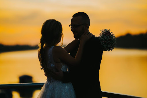 A romantic silhouette of a bride and groom embracing by a sunset lake, highlighting the intimate moments of Couple’s wedding planning.
