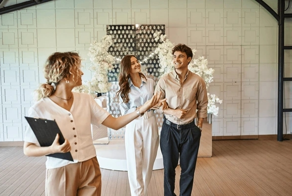 Wedding planner guiding a happy couple, representing the beginning of their comprehensive month-by-month wedding planning timeline journey.