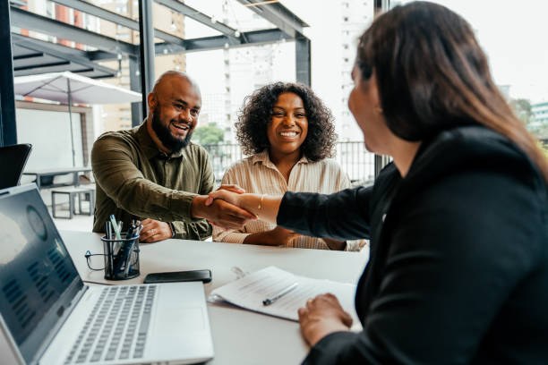 A couple shaking hands with a professional, highlighting their proactive approach to their wedding planning timeline by securing bookings early.