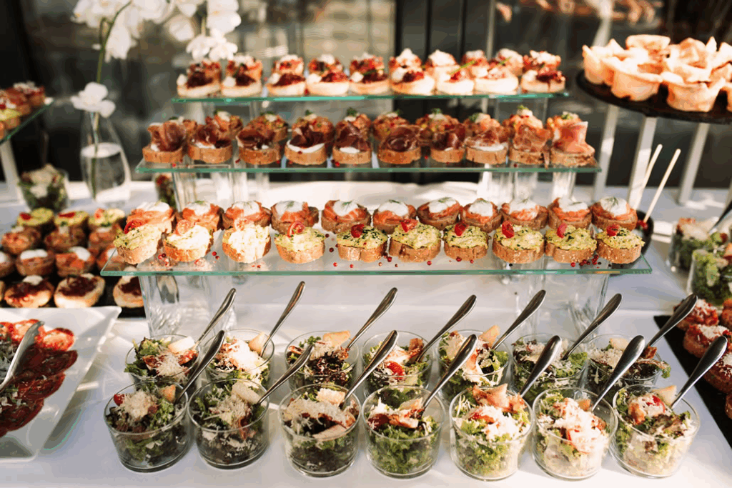 A lavish buffet spread with various appetizers and salads, showcasing adventurous food and drink wedding trends.
