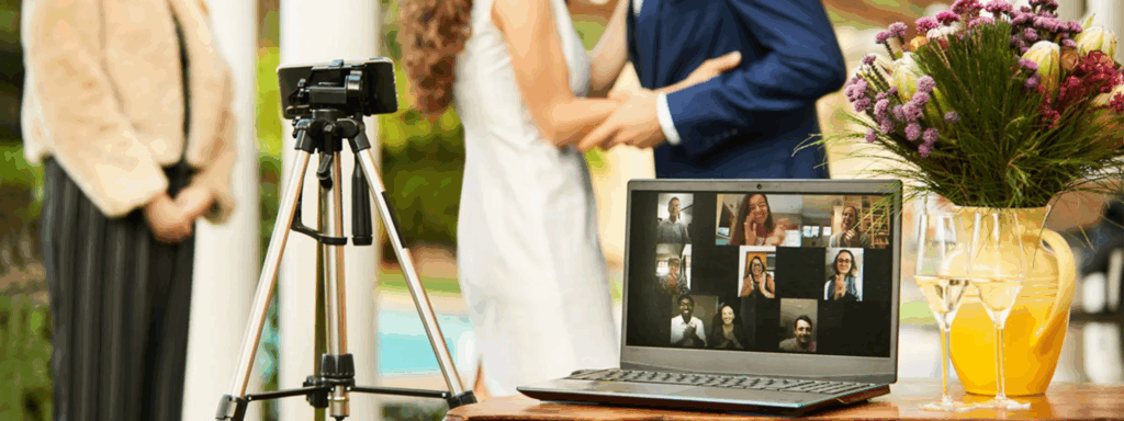 A laptop displaying a video call is set up at a wedding ceremony, alongside flowers and drinks, illustrating tech-savvy wedding trends for remote guests.