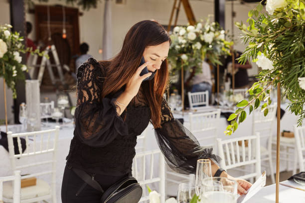 A focused wedding planner on the phone, arranging floral details and table settings, embodying the dedication behind dream weddings.