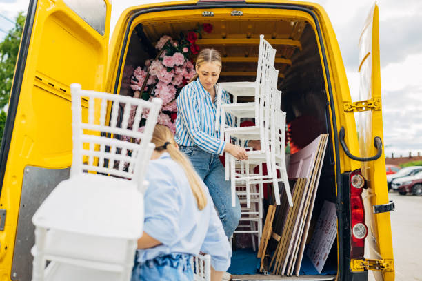 Two dedicated wedding planners unloading chairs and floral arrangements, showcasing the extensive behind-the-scenes work involved in setting up for a wedding.