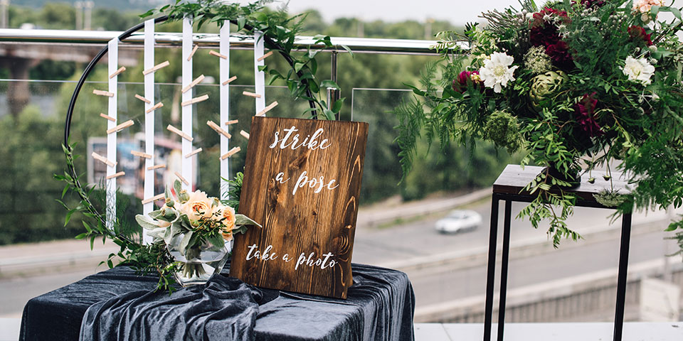 An outdoor wedding display with a "Strike a pose" sign and floral arrangements, thoughtfully designed to personalise your wedding.